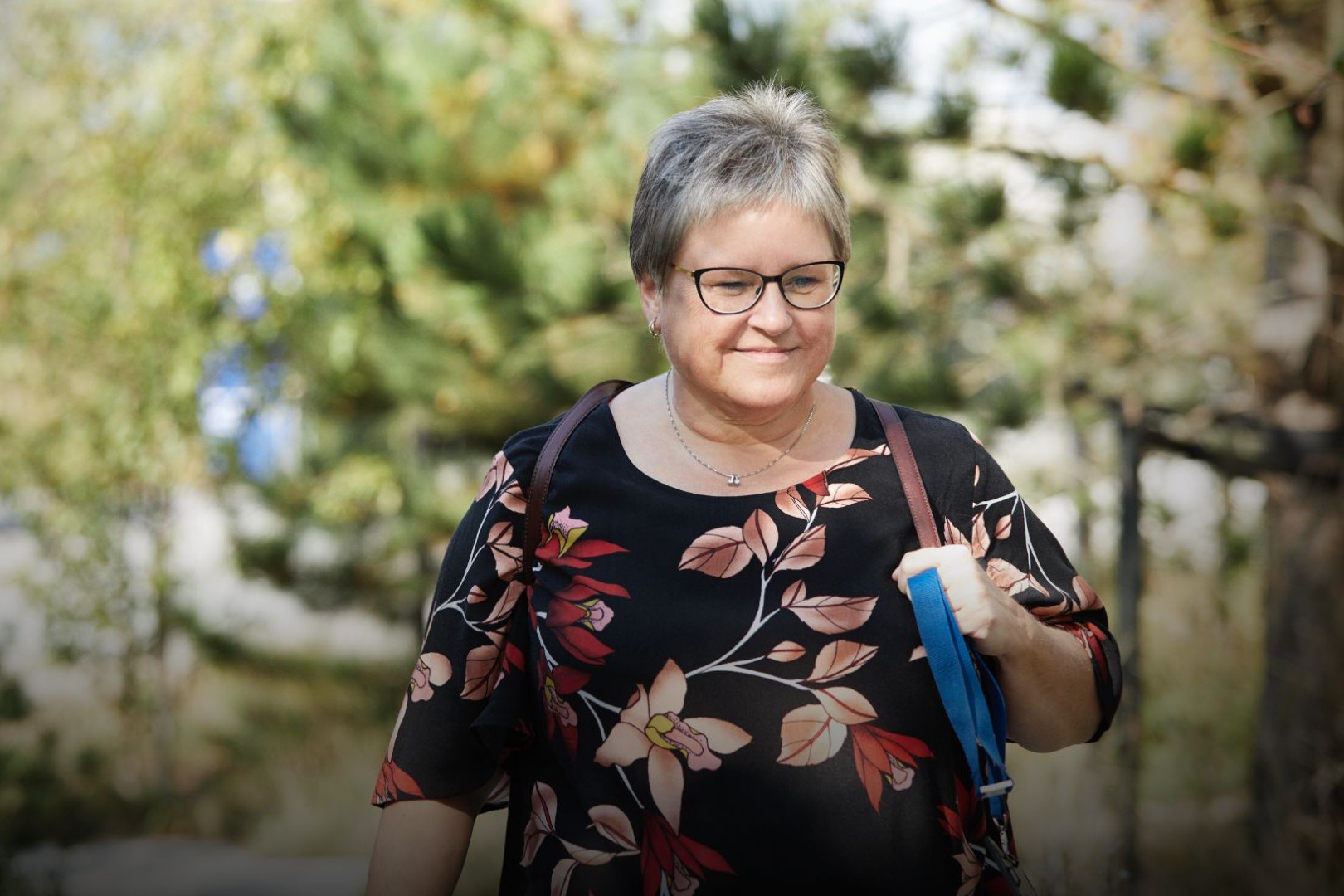 A woman walks outdoors carrying bag